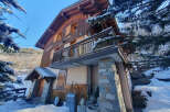 Nestled in a serene winter landscape, this charming wooden chalet offers a cozy retreat.