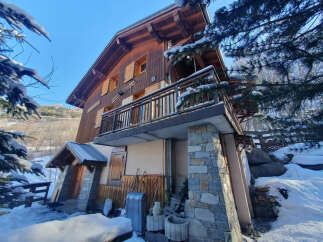 Nestled in a serene winter landscape, this charming wooden chalet offers a cozy retreat.