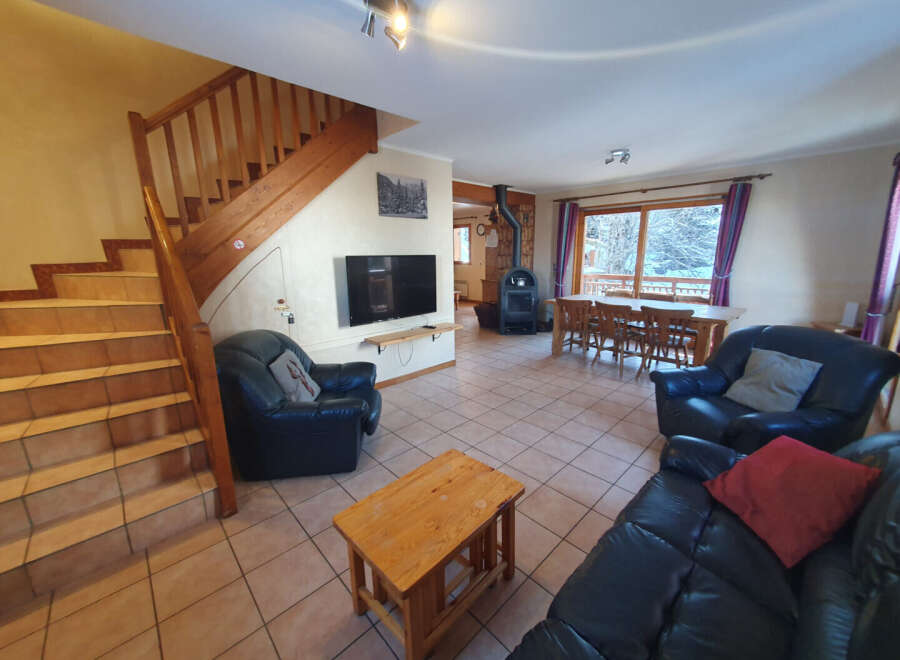 This cozy living space features a stunning staircase, a modern TV, and comfortable leather seating.