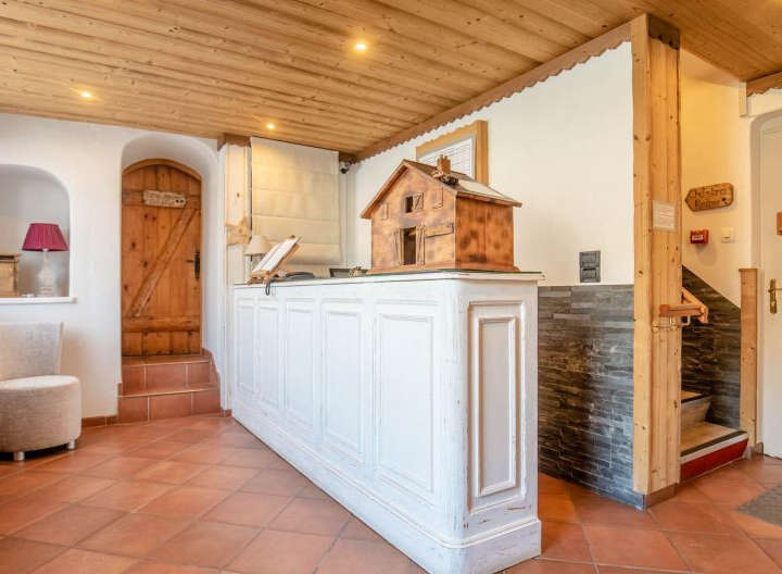 Step into the inviting reception area of this charming property, featuring a rustic wooden ceiling and a welcoming white reception desk.