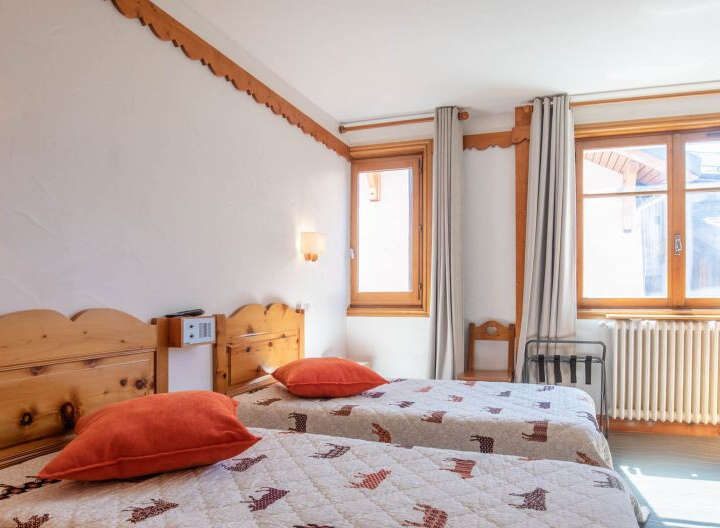 This cozy bedroom features two twin beds with comfortable bedding and vibrant orange pillows.
