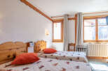 This cozy bedroom features two twin beds with comfortable bedding and vibrant orange pillows.