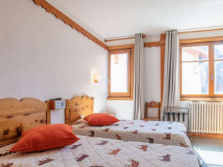 This cozy bedroom features two twin beds with comfortable bedding and vibrant orange pillows.