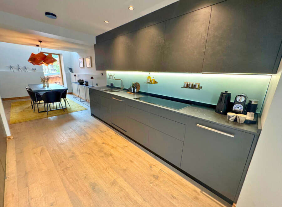 This modern kitchen boasts sleek, dark gray cabinetry and a minimalist design, perfect for contemporary living.