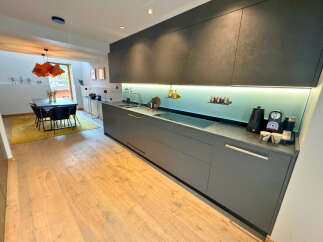 This modern kitchen boasts sleek, dark gray cabinetry and a minimalist design, perfect for contemporary living.