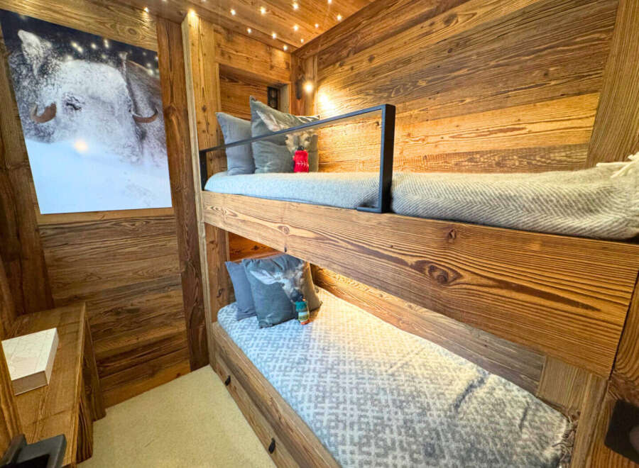 This cozy bunk bed room features beautiful wooden paneling and a charming aesthetic.