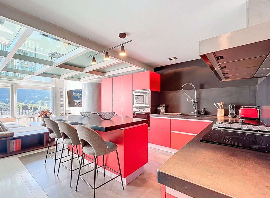 Experience modern luxury in this stunning kitchen! Featuring sleek red cabinetry, a stylish island with seating, and a state-of-the-art cooktop, this space is perfect for both cooking and entertaining.