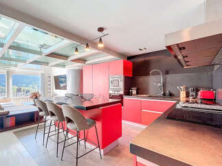 Experience modern luxury in this stunning kitchen! Featuring sleek red cabinetry, a stylish island with seating, and a state-of-the-art cooktop, this space is perfect for both cooking and entertaining.