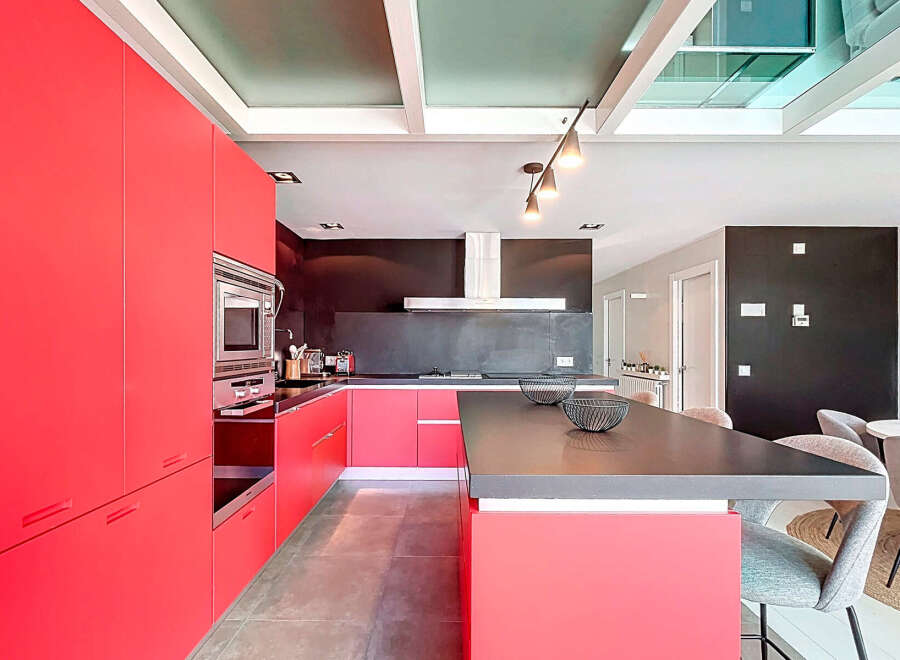 This modern kitchen boasts a sleek design with vibrant red cabinetry, offering ample storage and a bold aesthetic.