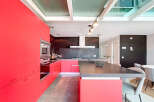 This modern kitchen boasts a sleek design with vibrant red cabinetry, offering ample storage and a bold aesthetic.
