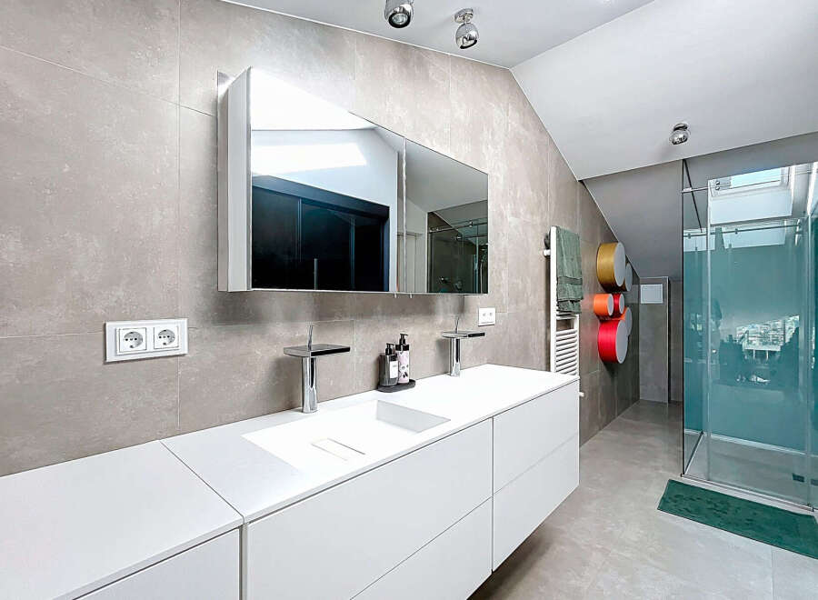 This modern bathroom boasts a sleek, minimalist design with a double vanity and a spacious walk-in shower.