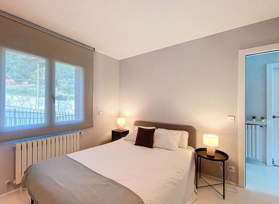 This cozy bedroom offers a serene retreat with its neutral color palette and ample natural light.