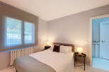 This cozy bedroom offers a serene retreat with its neutral color palette and ample natural light.