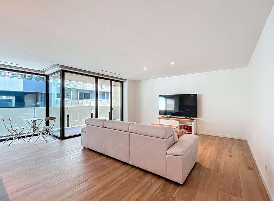Discover modern living in this stylish apartment featuring a spacious living area with a comfortable sofa and a large flat-screen TV.
