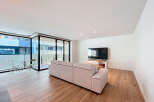 Discover modern living in this stylish apartment featuring a spacious living area with a comfortable sofa and a large flat-screen TV.