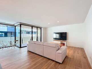 Discover modern living in this stylish apartment featuring a spacious living area with a comfortable sofa and a large flat-screen TV.