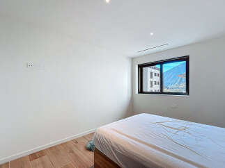 Discover the serenity of this modern bedroom, featuring a large window that frames stunning mountain views.