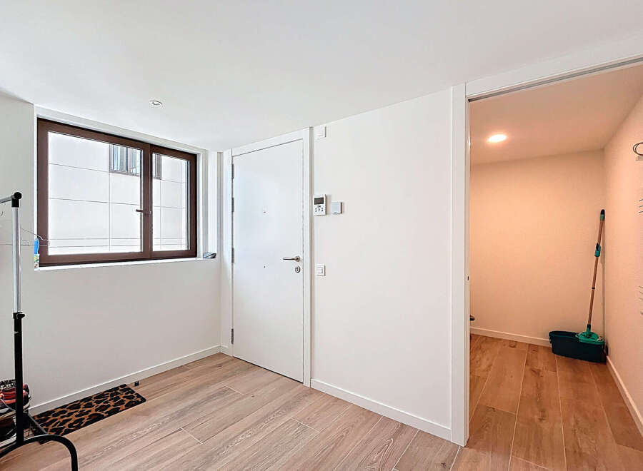 Step into this bright and airy entryway, featuring a modern design with sleek white walls and beautiful wooden flooring.