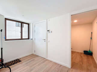 Step into this bright and airy entryway, featuring a modern design with sleek white walls and beautiful wooden flooring.