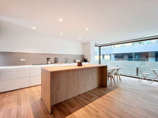 This modern kitchen boasts a sleek design with a large wooden island, perfect for meal preparation and entertaining.
