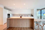 This modern kitchen boasts a sleek design with a large wooden island, perfect for meal preparation and casual dining.