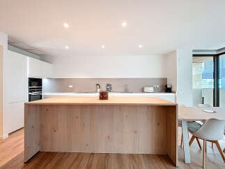 This modern kitchen boasts a sleek design with a large wooden island, perfect for meal preparation and casual dining.