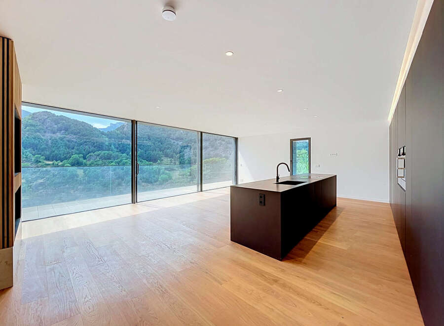 Experience modern living in this stunning open-plan kitchen and living area, boasting panoramic mountain views through expansive floor-to-ceiling windows.