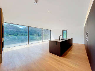 Experience modern living in this stunning open-plan kitchen and living area, boasting panoramic mountain views through expansive floor-to-ceiling windows.