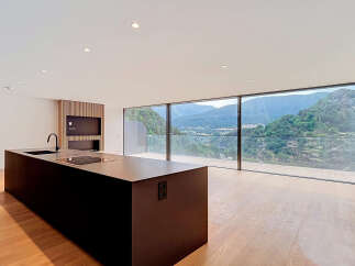 Experience modern living with this stunning open-concept kitchen and living area, boasting panoramic mountain views through expansive floor-to-ceiling windows.