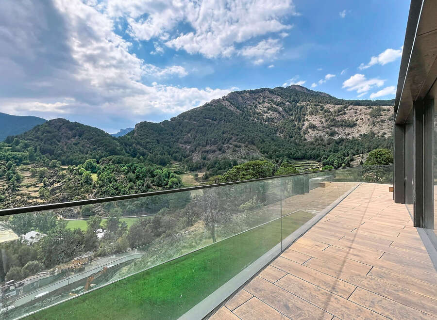 Experience breathtaking mountain views from this stunning property, featuring a spacious balcony with a modern glass railing.