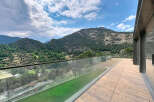 Experience breathtaking mountain views from this stunning property, featuring a spacious balcony with a modern glass railing.