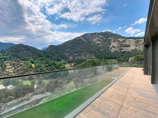Experience breathtaking mountain views from this stunning property, featuring a spacious balcony with a modern glass railing.
