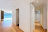 Experience modern living in this spacious hallway featuring elegant hardwood floors and a stunning view of lush greenery through a large window.