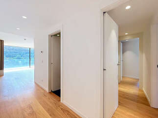 Experience modern living in this spacious hallway featuring elegant hardwood floors and a stunning view of lush greenery through a large window.