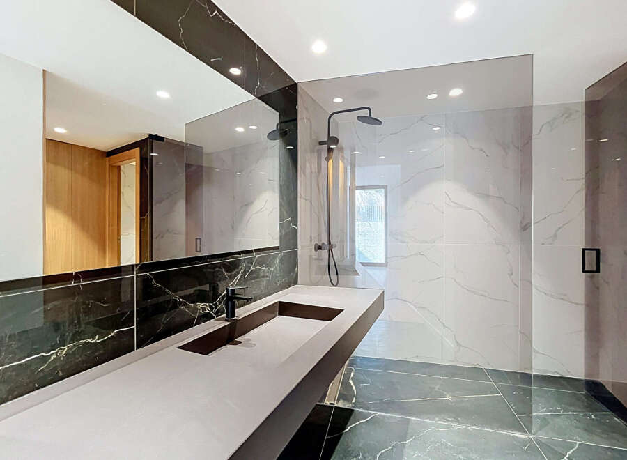 Experience modern luxury in this stunning bathroom featuring a sleek vanity with a minimalist black faucet and a spacious countertop.