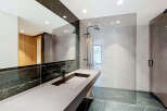 Experience modern luxury in this stunning bathroom featuring a sleek vanity with a minimalist black faucet and a spacious countertop.