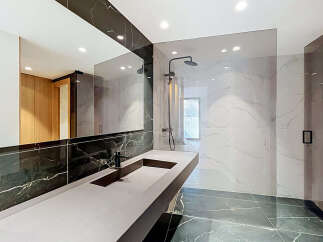 Experience modern luxury in this stunning bathroom featuring a sleek vanity with a minimalist black faucet and a spacious countertop.