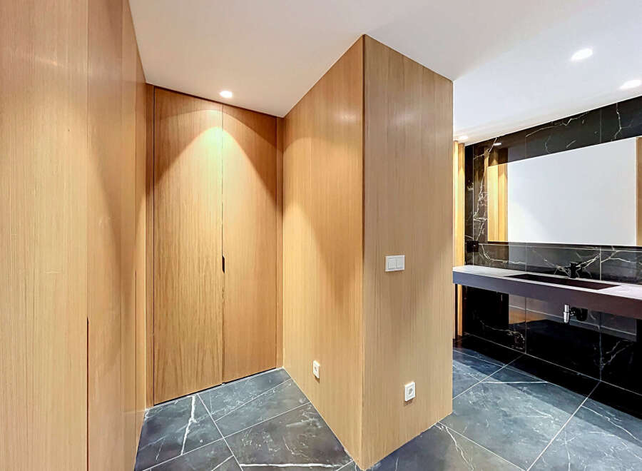 Experience modern luxury in this stunning bathroom featuring a sleek vanity with a dark countertop and integrated sink, complemented by a large, illuminated mirror.