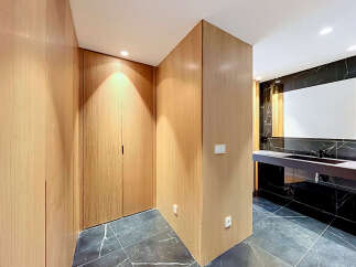 Experience modern luxury in this stunning bathroom featuring a sleek vanity with a dark countertop and integrated sink, complemented by a large, illuminated mirror.