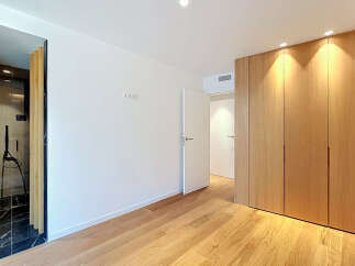 Experience modern living in this beautifully appointed room featuring a sleek, integrated wardrobe with natural wood finishes.