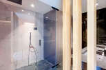 Experience modern luxury in this stunning bathroom featuring a sleek glass-enclosed shower with marble-look tiles and a sophisticated black shower system.