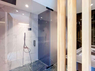 Experience modern luxury in this stunning bathroom featuring a sleek glass-enclosed shower with marble-look tiles and a sophisticated black shower system.