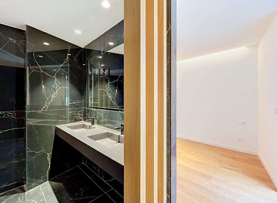 Experience modern luxury in this stunning bathroom featuring a sleek double vanity with a black marble backdrop.