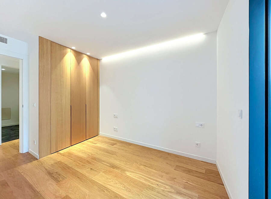 Experience modern living in this beautifully designed room featuring a sleek, floor-to-ceiling wooden wardrobe that offers ample storage.