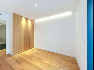 Experience modern living in this beautifully designed room featuring a sleek, floor-to-ceiling wooden wardrobe that offers ample storage.