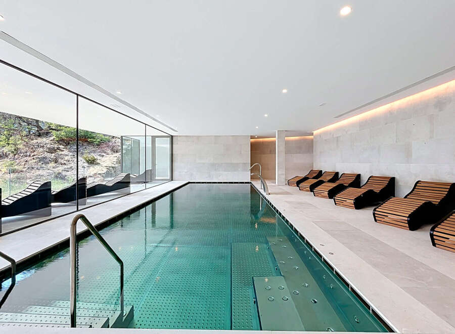 Experience ultimate relaxation in this luxurious indoor swimming pool area, featuring a stunning lap pool with crystal-clear water and integrated spa jets.