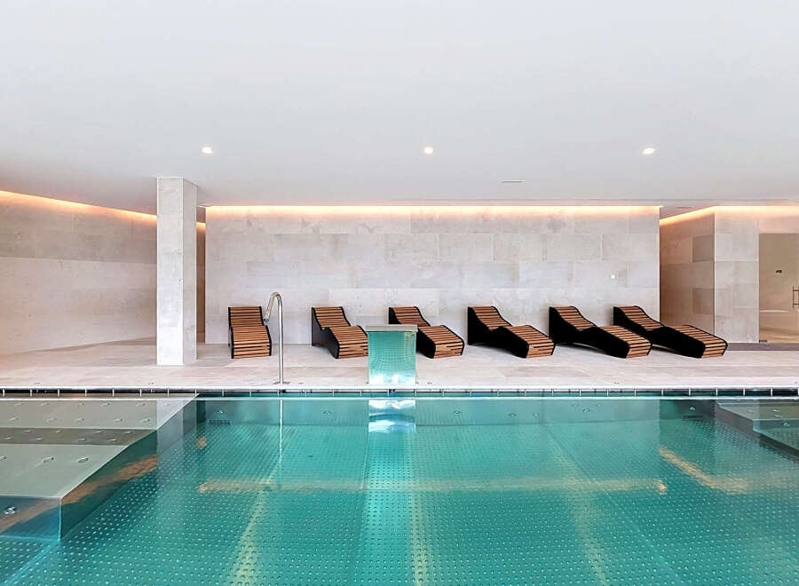 Experience ultimate relaxation in this luxurious indoor pool area, featuring sleek lounge chairs perfect for unwinding.