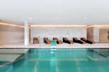 Experience ultimate relaxation in this luxurious indoor pool area, featuring sleek lounge chairs perfect for unwinding.