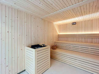 Experience ultimate relaxation in this beautifully crafted wooden sauna, featuring ample seating and modern heating elements.