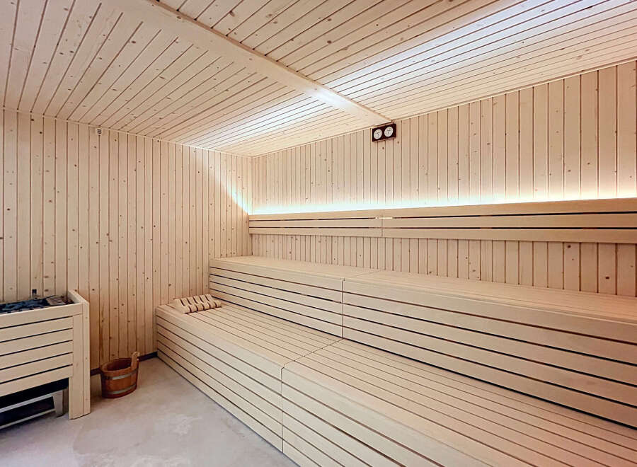Experience ultimate relaxation in this luxurious sauna, featuring natural wood paneling and tiered seating for optimal comfort.